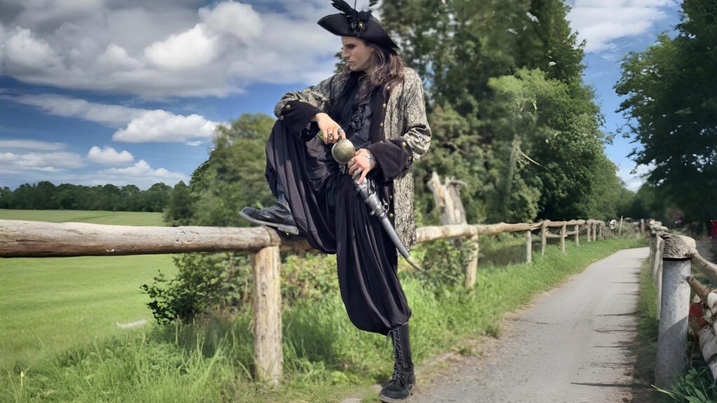 Regal pirate coat with gold brocade design from The Pirate Dressing, styled with black pirate pants and tricorn hat.