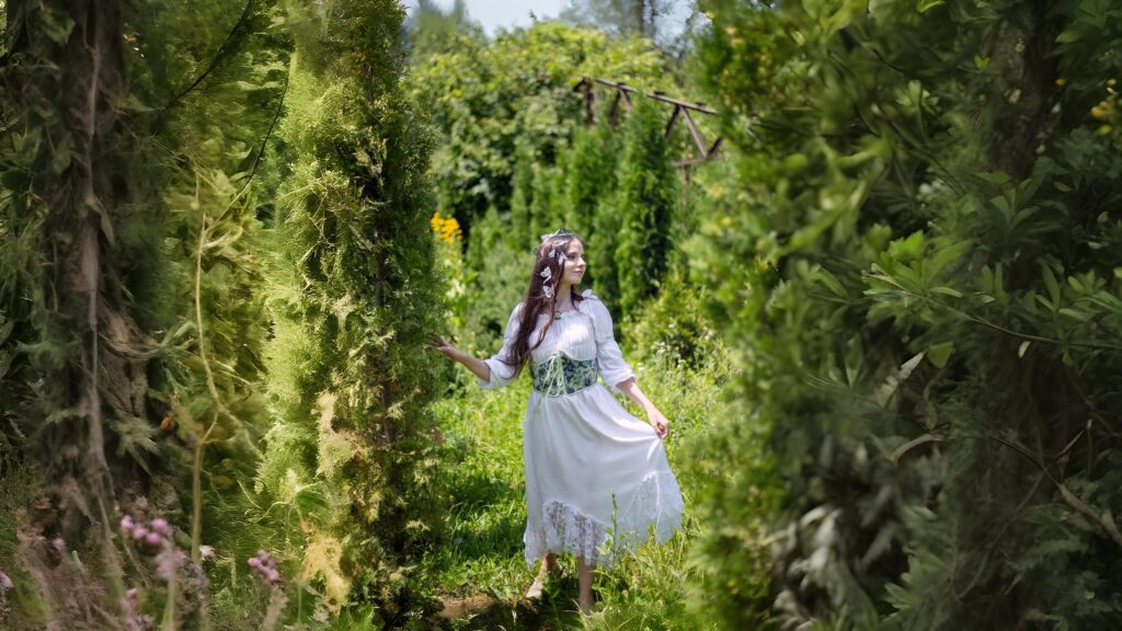 Woman in a medieval-inspired white dress with lace hem and green corset walking barefoot in an enchanted garden.