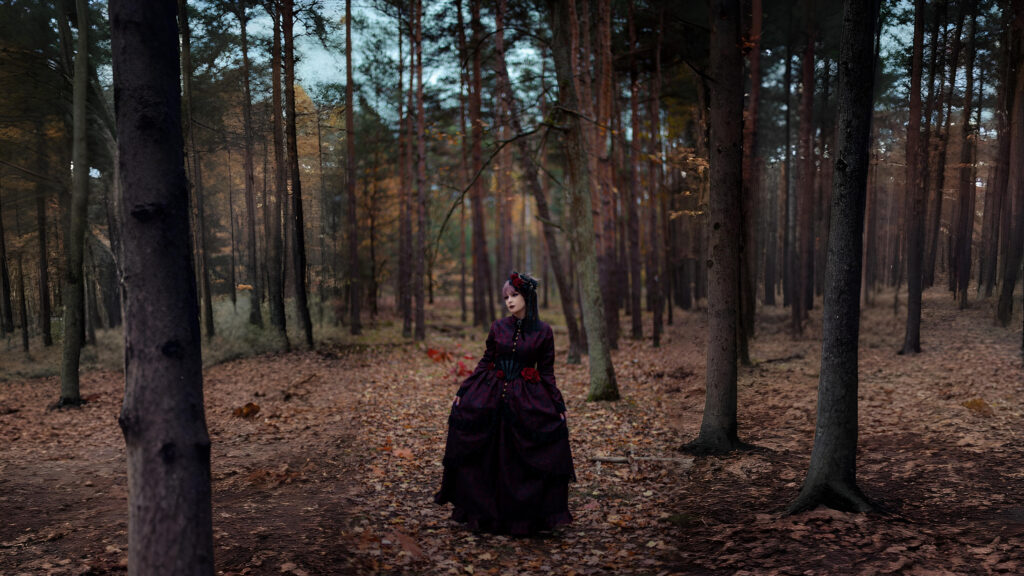 Woman wearing a dark Renaissance-style gown with floral details standing in a misty autumn forest, showcasing vintage elegance and historical fashion vibes.
