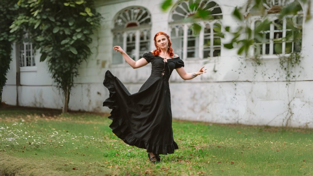 Black medieval-inspired dress with puff sleeves being worn by a woman posing outdoors in front of an old building, creating a graceful and historic aesthetic.